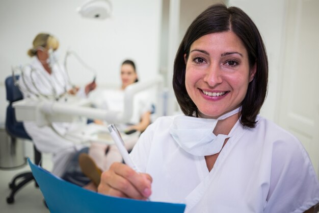 Femme dentiste écrit un rapport dans une clinique dentaire