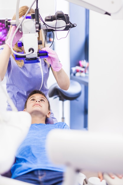 Femme dentiste examine les dents du garçon en clinique