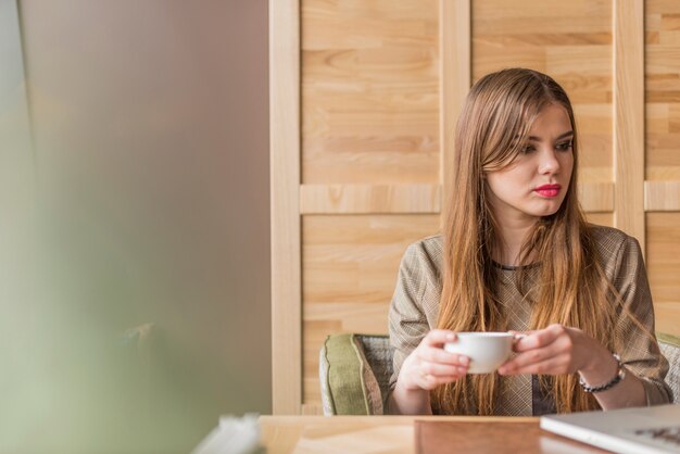 femme détendue avec une tasse de thé en regardant vers son ordinateur portable