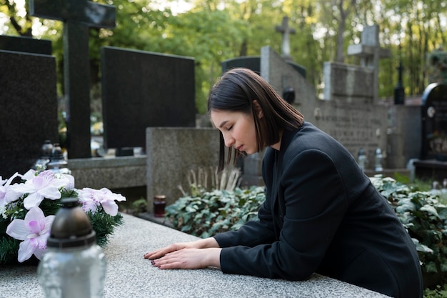 Femme en deuil dans le cimetière à côté de la tombe