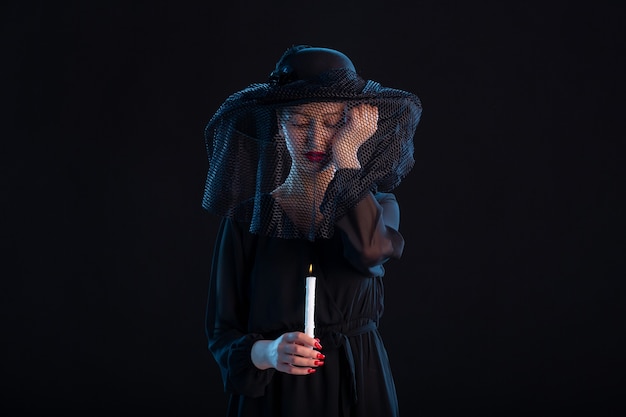 Photo gratuite femme en deuil vêtue de noir avec une bougie allumée sur une surface noire tristesse mort funéraire