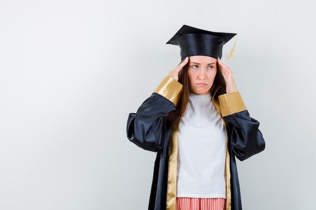 Femme diplômée souffrant de maux de tête en uniforme, vêtements décontractés et à la vue fatiguée, de face.