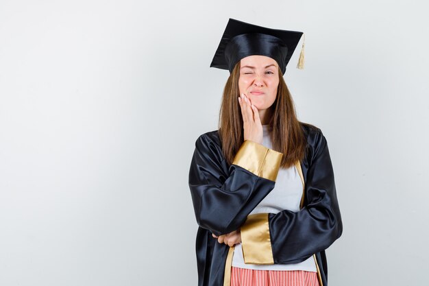 Femme diplômée tenant la main sur le menton dans des vêtements décontractés, uniforme et à la pensif. vue de face.