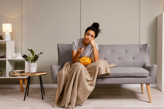 Femme, sur, divan, regarder télé, et, manger chips