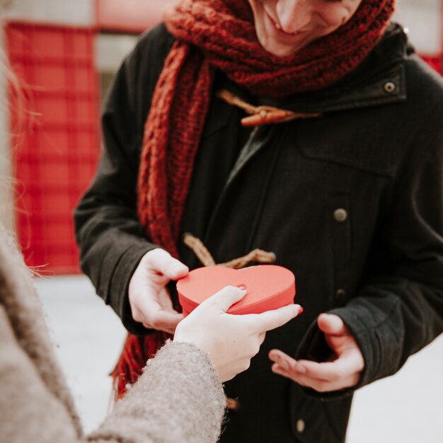 Femme donnant le cadeau en forme de coeur au petit ami