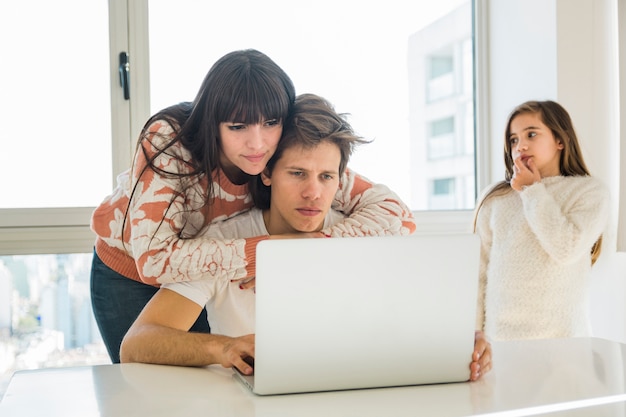 Femme donnant un soutien à son mari travaillant sur ordinateur portable à la maison