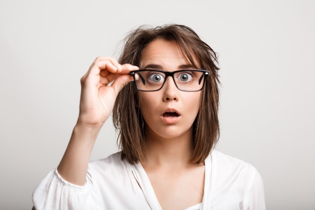 Femme drôle avec coupe de cheveux en désordre ébouriffé à travers des lunettes