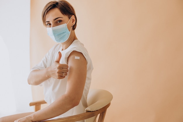 Femme avec du plâtre sur l'épaule assise sur une chaise après la vaccination