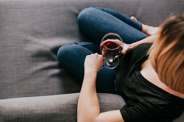 Femme avec du vin rouge sur le canapé