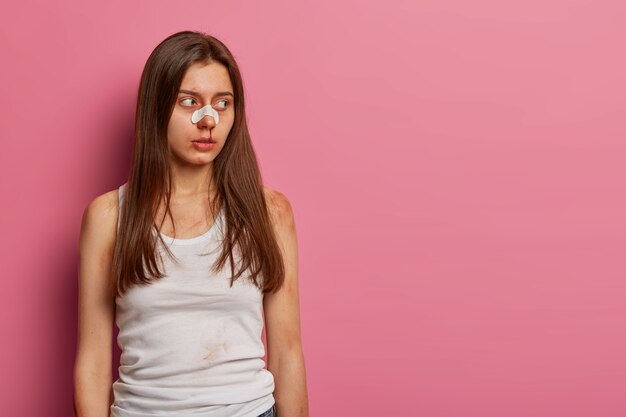 Femme avec des ecchymoses et le nez cassé, étant gravement blessée