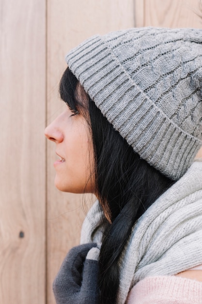 Femme en écharpe et bonnet sur fond en bois