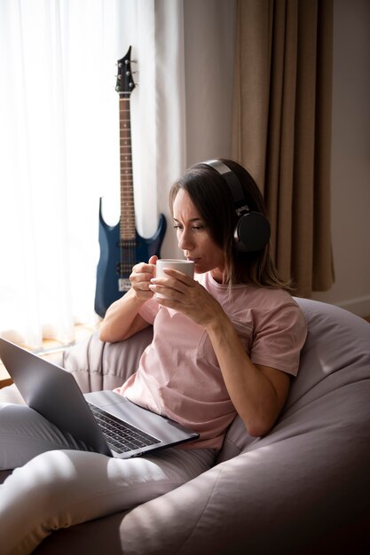 Femme écoutant de la musique avec des écouteurs à la maison