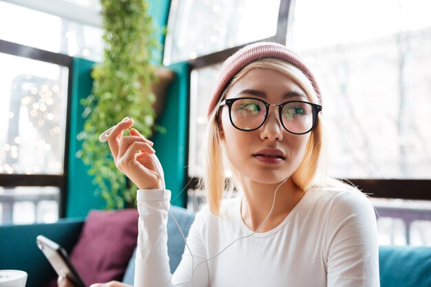 Femme écoutant de la musique et regardant de côté au café.