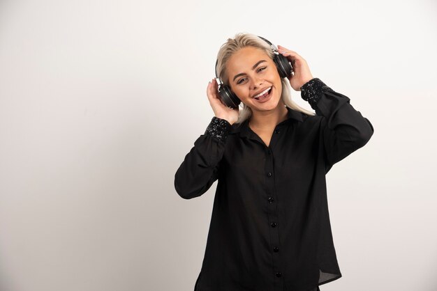 Femme écoute chanson avec un casque sur fond blanc. Photo de haute qualité