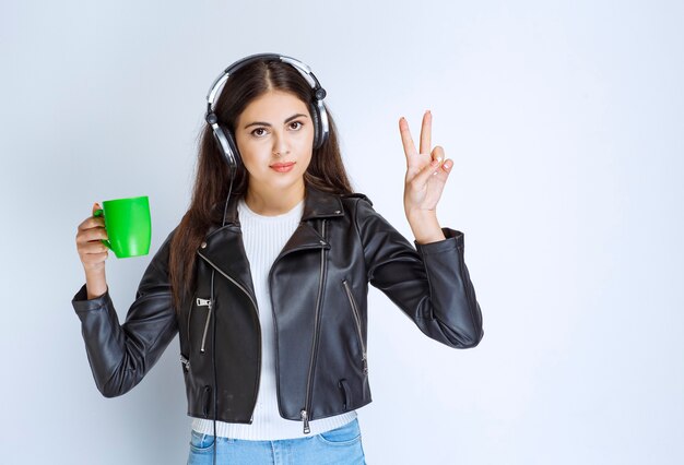 femme avec des écouteurs ayant une tasse de thé vert.