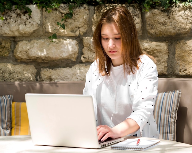 Femme, écouteurs, fonctionnement, ordinateur portable, dehors