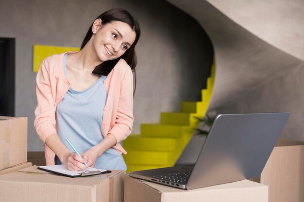 Femme écrivant des commandes de la boutique en ligne pour livrer