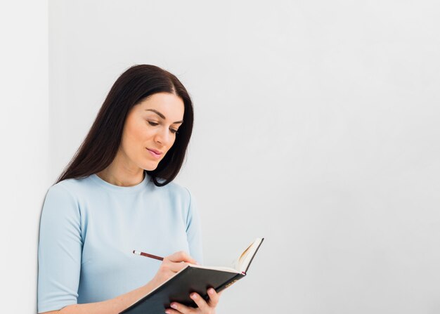 Femme écrivant dans un cahier avec un crayon