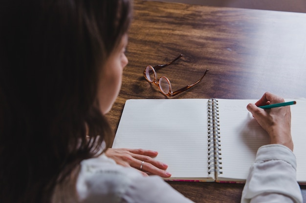 Femme écrivant dans un journal sur table en bois