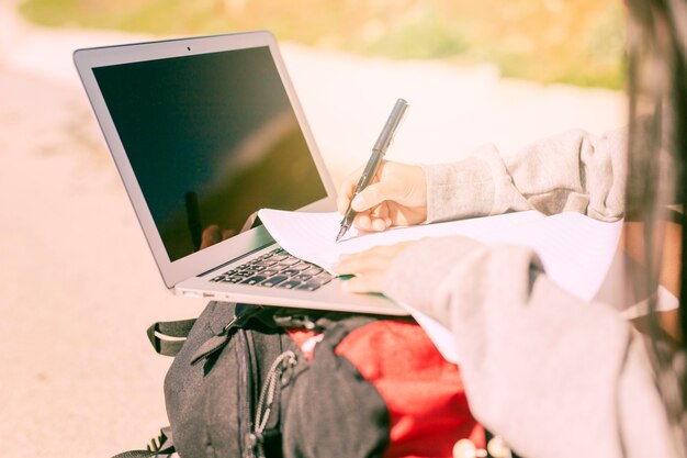 Femme écrivant à la main sur un cahier en journée ensoleillée