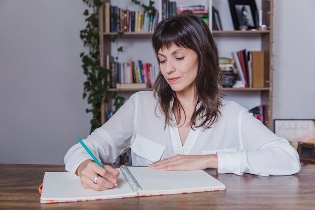 Femme écrivant quelque chose dans un journal