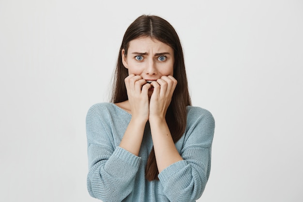 Femme effrayée effrayée se mordant les ongles, fronçant les sourcils effrayée