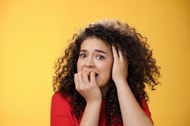 Une femme effrayée qui réfléchit trop à la peur d'avoir des problèmes à se mordre les doigts tenant la main sur la tête de désespoir...