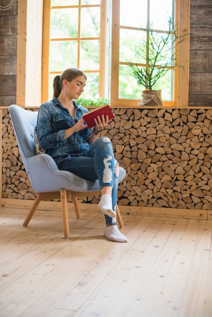 Femme élégante assise sur une chaise et un livre de lecture