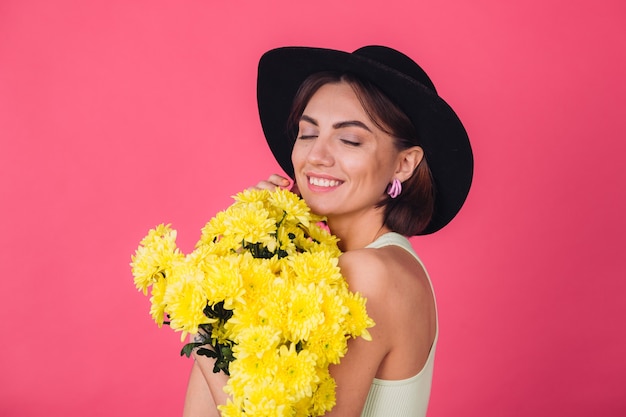 Femme élégante au chapeau, étreignant un grand bouquet d'asters jaunes, humeur printanière, émotions heureuses, espace isolé, yeux fermés