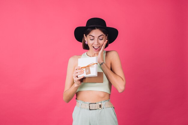 Femme élégante au chapeau sur un mur rouge rose