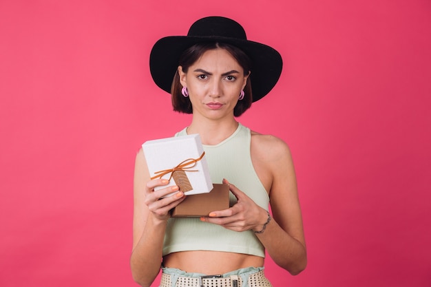 Femme élégante au chapeau sur un mur rouge rose