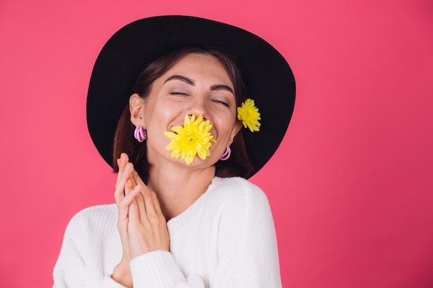 Femme élégante au chapeau, souriant avec deux asters jaunes, mignon tenir une fleur dans l'humeur du printemps de la bouche, espace isolé des émotions heureuses