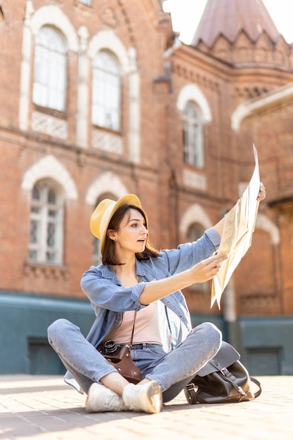 Femme élégante avec chapeau vérifiant la carte locale