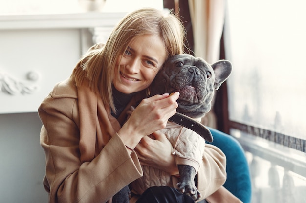 Femme élégante dans un manteau marron avec bouledogue noir