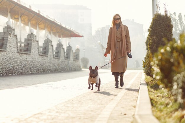 Femme élégante dans un manteau marron avec bouledogue noir