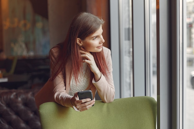 Femme élégante dans une veste rose passer du temps dans un café