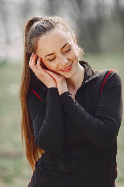 Femme élégante dans un vêtement noir dans un parc de printemps