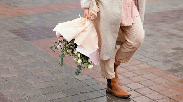Femme élégante dans la ville tenant un bouquet de fleurs
