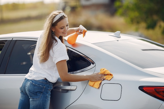 Femme élégante essuie la voiture avec un chiffon