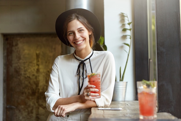 Femme élégante avec grand chapeau assis au café