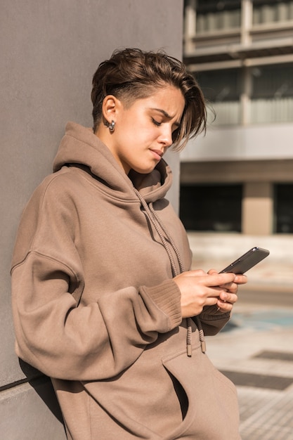 Femme élégante portant des vêtements de sport tout en vérifiant son téléphone