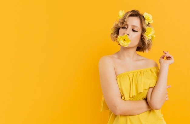 Photo gratuite femme élégante posant avec une fleur couvrant sa bouche