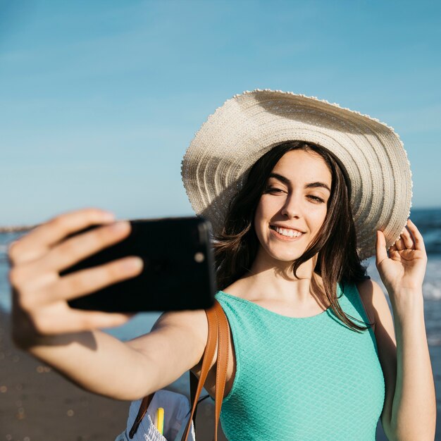 Femme élégante prenant selfie à la plage