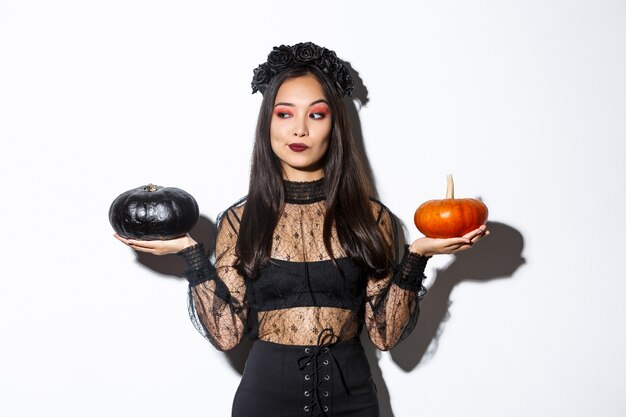 Femme élégante réfléchie en costume de sorcière, cueillette de citrouille pour halloween