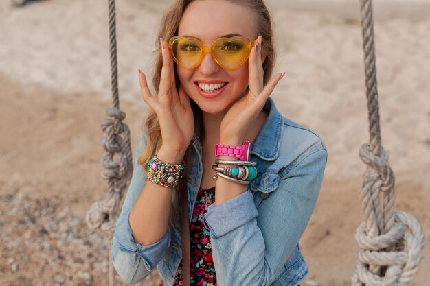 Femme élégante en robe d'été vacances sur la plage en sunglasess jaune coloré souriant heureux