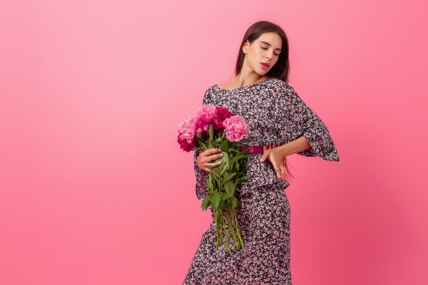 Femme élégante sur rose en robe à la mode d'été posant avec bouquet de fleurs de pivoine