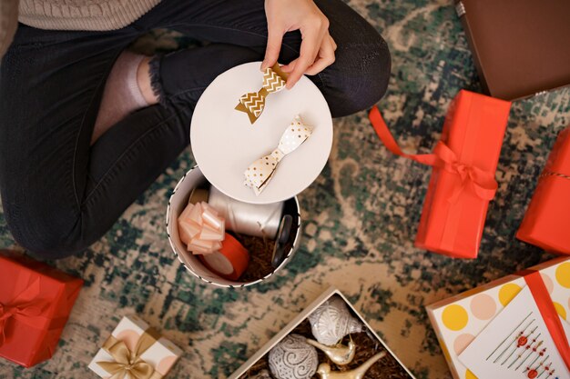 Photo gratuite femme emballage cadeau de noël assis sur la carpée dans le salon