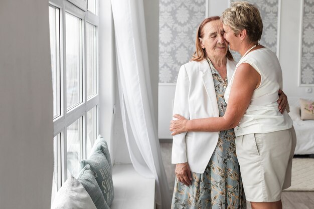 Femme embrassant sa mère âgée à la maison