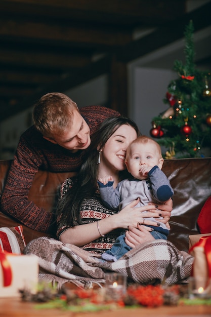 Femme embrassant son bébé sur sa tête tandis que les sourires de père