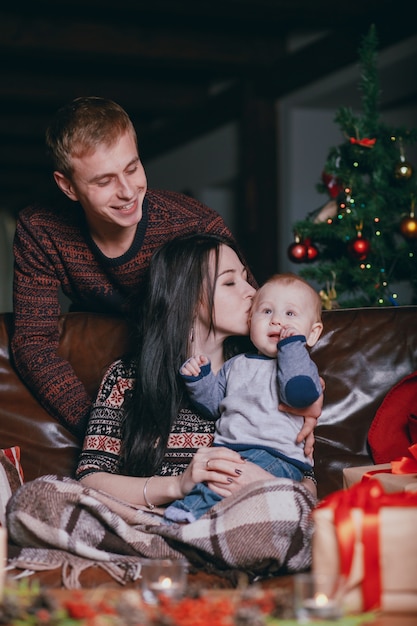 Femme embrassant son bébé sur sa tête tandis que les sourires de père